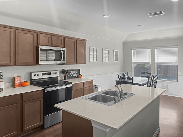 kitchen featuring sink, dark wood-type flooring, light stone counters, a kitchen island with sink, and appliances with stainless steel finishes