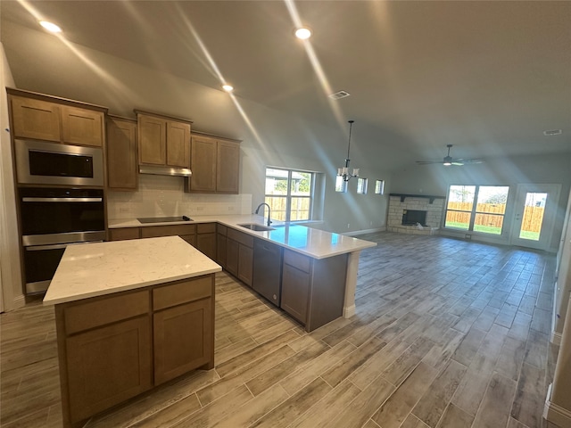 kitchen featuring ceiling fan with notable chandelier, light hardwood / wood-style flooring, sink, a fireplace, and appliances with stainless steel finishes