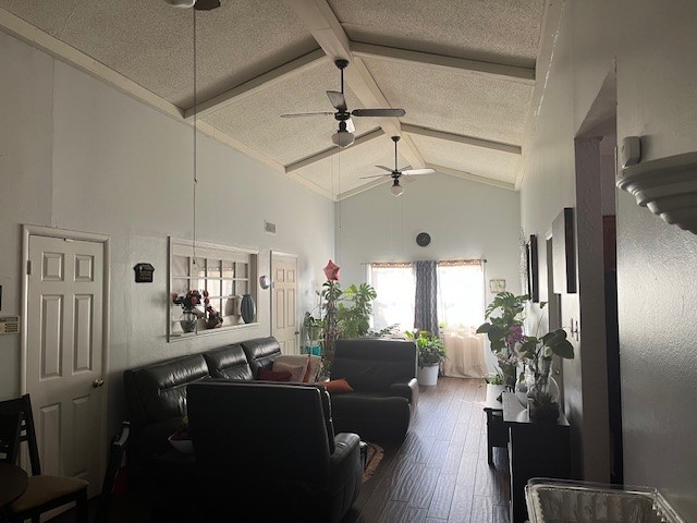 living room with a textured ceiling, high vaulted ceiling, wood finished floors, visible vents, and beamed ceiling