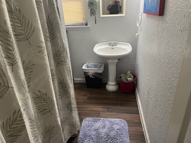 bathroom with baseboards, a textured wall, a sink, and wood tiled floor