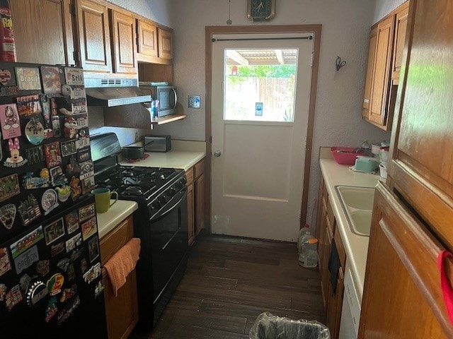 kitchen featuring black gas range, extractor fan, fridge, and dark wood-type flooring