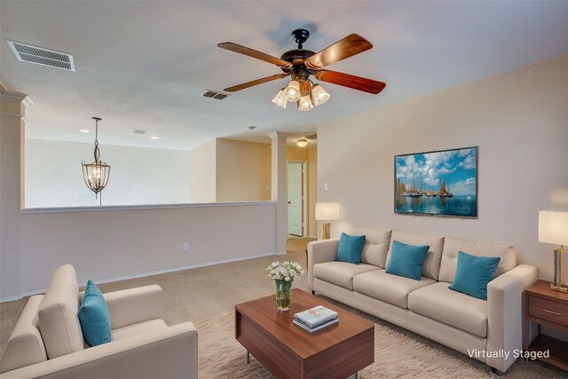 carpeted living room featuring ceiling fan with notable chandelier