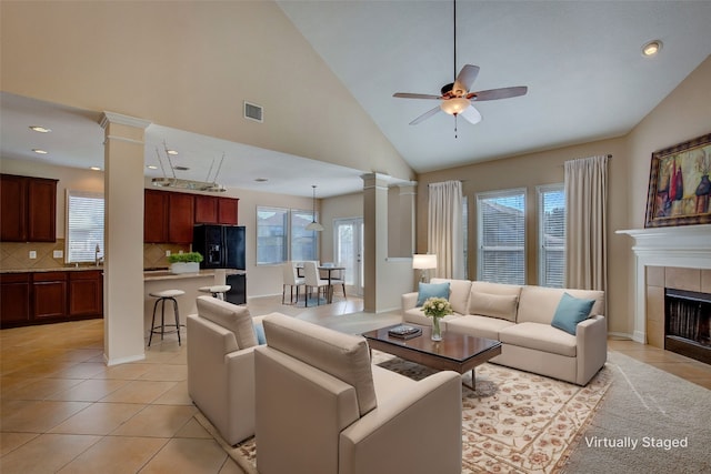 living room with a fireplace, ceiling fan, high vaulted ceiling, and light tile patterned floors