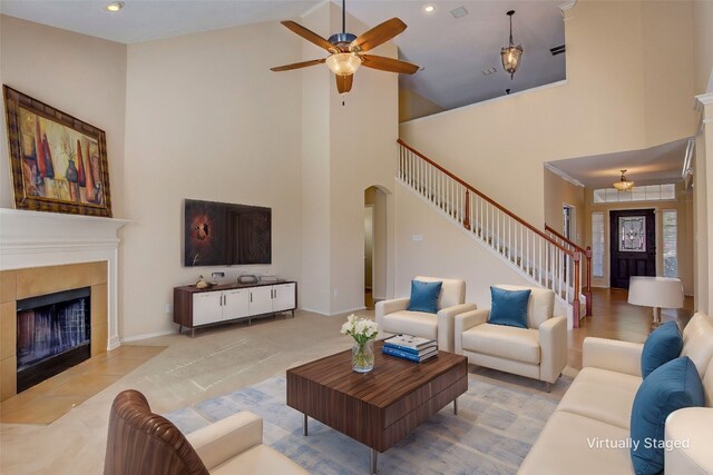 living room featuring a fireplace, light hardwood / wood-style floors, ceiling fan, and high vaulted ceiling