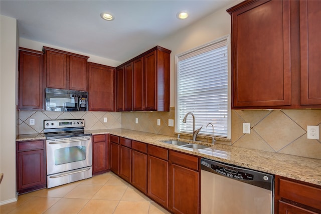 kitchen featuring stainless steel appliances, sink, backsplash, and light stone countertops