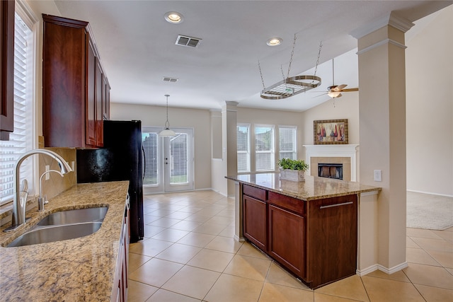 kitchen featuring light stone counters, light tile patterned flooring, ornate columns, hanging light fixtures, and sink