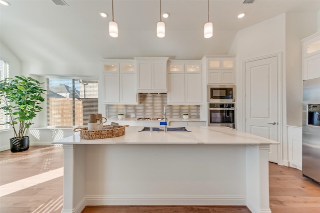 kitchen featuring decorative light fixtures, stainless steel appliances, white cabinets, and decorative backsplash