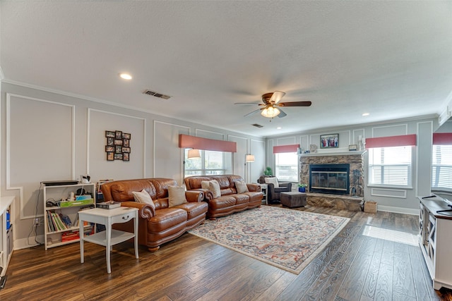 living room featuring ceiling fan, dark wood-type flooring, crown molding, and a fireplace