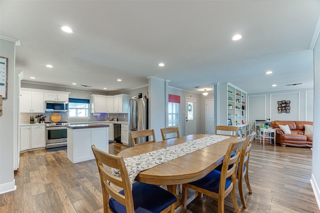 dining room with plenty of natural light, ornamental molding, and light hardwood / wood-style flooring