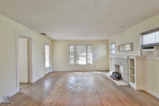 unfurnished living room with a fireplace, a textured ceiling, light hardwood / wood-style floors, and cooling unit