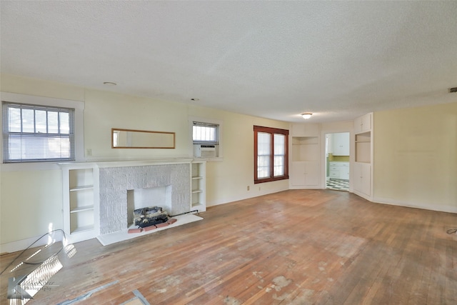 unfurnished living room featuring a textured ceiling, hardwood / wood-style flooring, and plenty of natural light