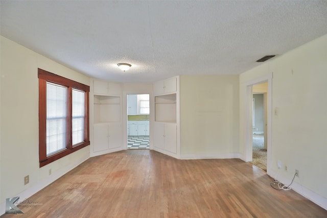 unfurnished room featuring a textured ceiling and light hardwood / wood-style floors