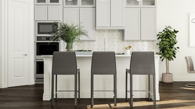 kitchen with white cabinets, stainless steel oven, dark hardwood / wood-style flooring, and tasteful backsplash