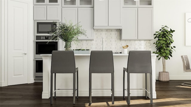 kitchen with white cabinets, stainless steel oven, dark hardwood / wood-style flooring, and tasteful backsplash