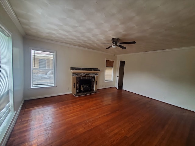 unfurnished living room featuring ornamental molding, a tiled fireplace, dark hardwood / wood-style floors, and ceiling fan