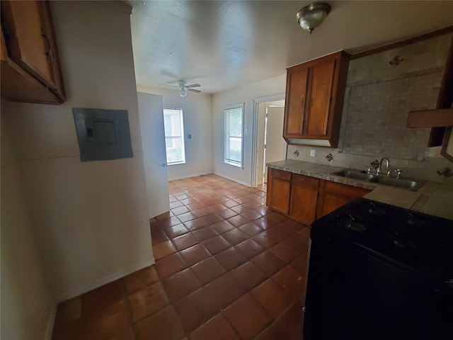 kitchen with electric panel, sink, tasteful backsplash, dark tile patterned floors, and ceiling fan