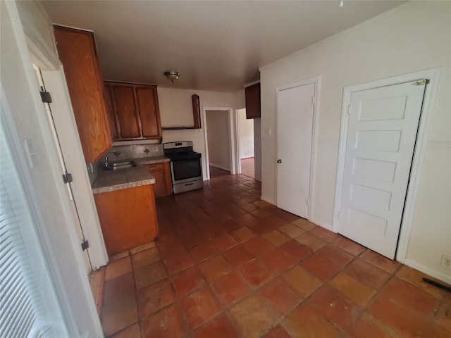 kitchen featuring sink, dark tile patterned floors, and stainless steel range