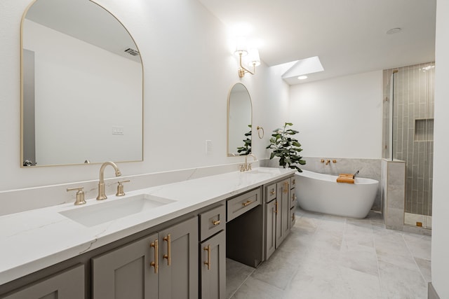 bathroom with plus walk in shower, vanity, a skylight, and tile patterned floors