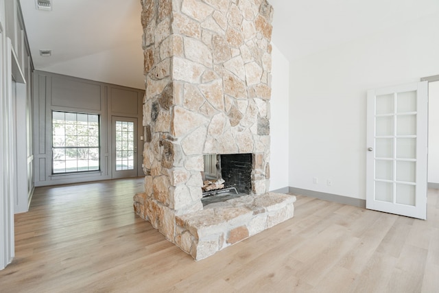 unfurnished living room featuring high vaulted ceiling, a fireplace, and light hardwood / wood-style floors