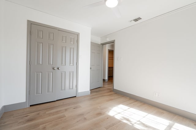 unfurnished bedroom featuring ceiling fan, a closet, and light hardwood / wood-style flooring