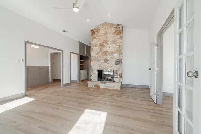 unfurnished living room featuring ceiling fan, high vaulted ceiling, a fireplace, french doors, and light wood-type flooring