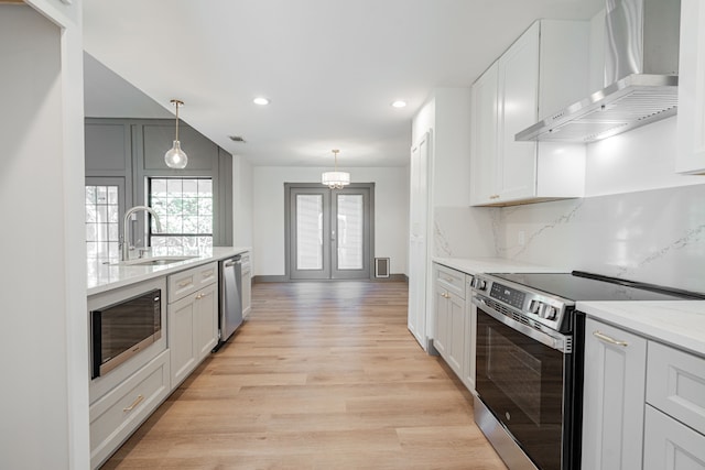 kitchen featuring white cabinets, wall chimney exhaust hood, sink, and appliances with stainless steel finishes