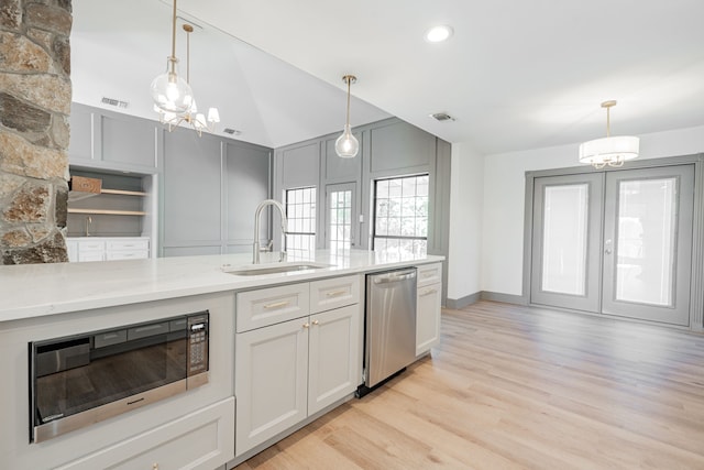 kitchen with sink, light stone counters, black microwave, light wood-type flooring, and stainless steel dishwasher