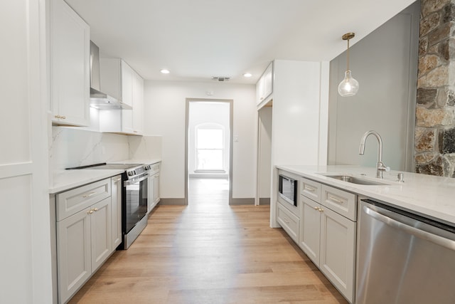 kitchen featuring stainless steel appliances, sink, white cabinets, and wall chimney exhaust hood