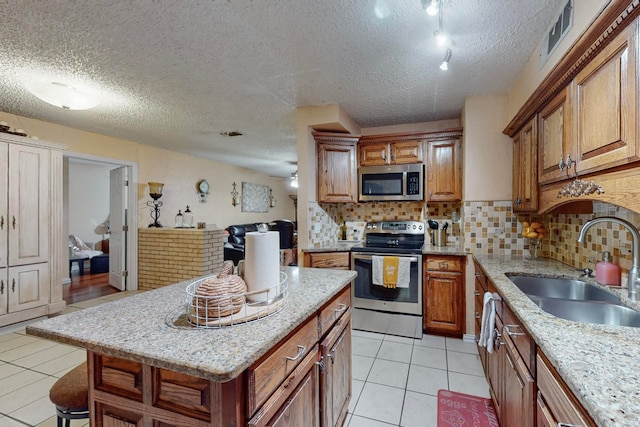 kitchen with tasteful backsplash, stainless steel appliances, a textured ceiling, a kitchen bar, and sink