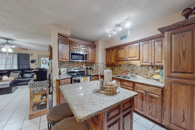 kitchen featuring a kitchen island, appliances with stainless steel finishes, sink, and a textured ceiling