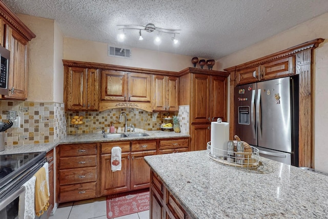 kitchen with a textured ceiling, stainless steel appliances, sink, and light tile patterned flooring