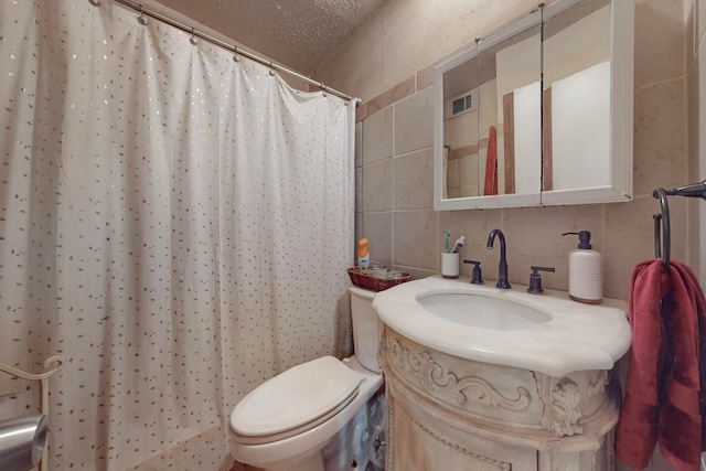 bathroom with a textured ceiling, curtained shower, vanity, toilet, and tile walls