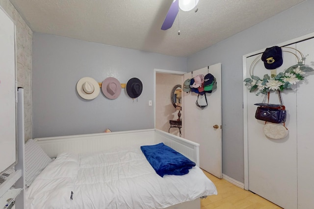 bedroom featuring light wood-type flooring, a textured ceiling, and ceiling fan