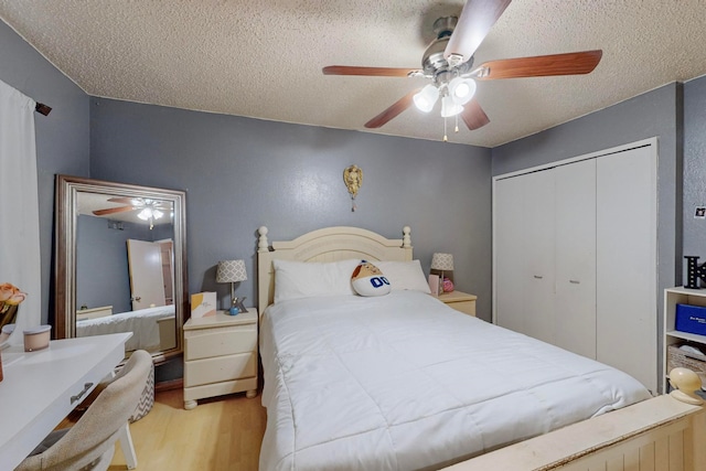 bedroom with ceiling fan, a textured ceiling, a closet, and light wood-type flooring