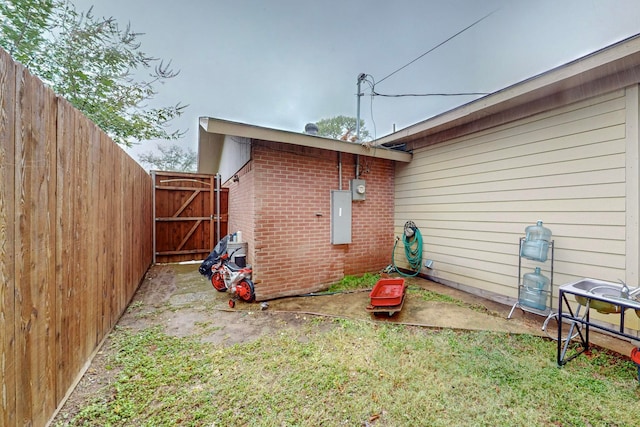 view of side of property with electric panel and a lawn