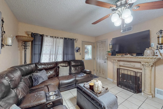 tiled living room with a textured ceiling, plenty of natural light, and ceiling fan