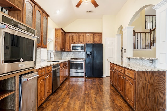 kitchen featuring dark wood-type flooring, sink, vaulted ceiling, stainless steel appliances, and decorative backsplash