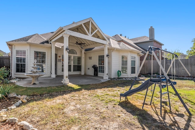 back of property with ceiling fan, a playground, a patio area, and a lawn