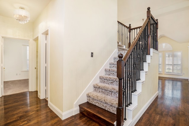 staircase featuring an inviting chandelier, hardwood / wood-style floors, and vaulted ceiling