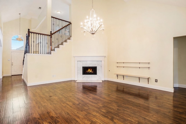 unfurnished living room featuring an inviting chandelier, a tiled fireplace, dark wood-type flooring, and high vaulted ceiling