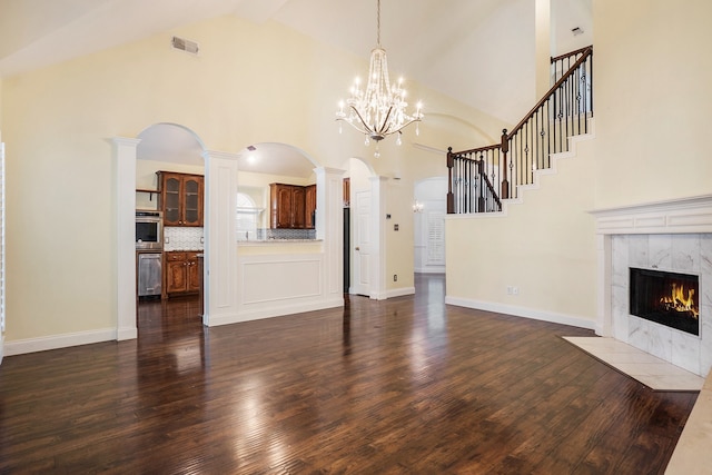 unfurnished living room with ornate columns, dark hardwood / wood-style floors, a fireplace, and high vaulted ceiling