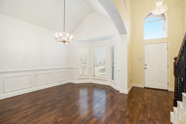 foyer with dark hardwood / wood-style flooring, a wealth of natural light, a notable chandelier, and high vaulted ceiling