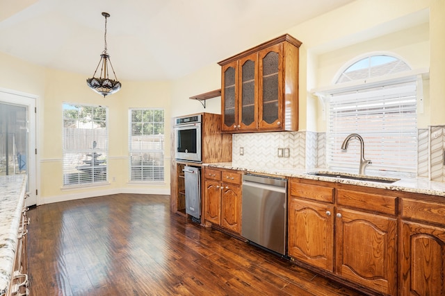 kitchen featuring pendant lighting, sink, light stone countertops, decorative backsplash, and stainless steel dishwasher