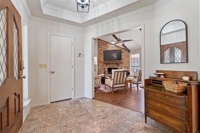 entrance foyer featuring ceiling fan, hardwood / wood-style floors, crown molding, and a brick fireplace