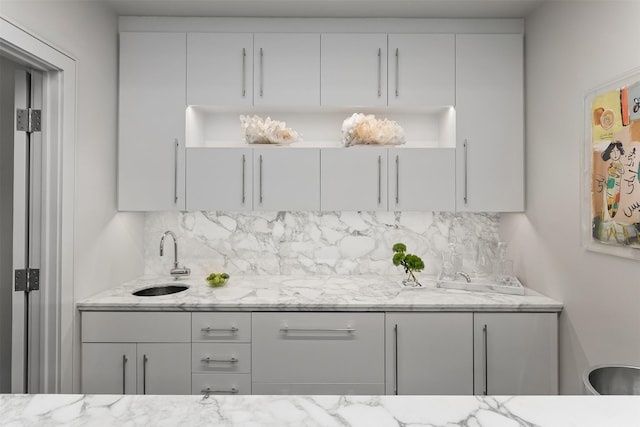 bar with light stone countertops, decorative backsplash, and sink