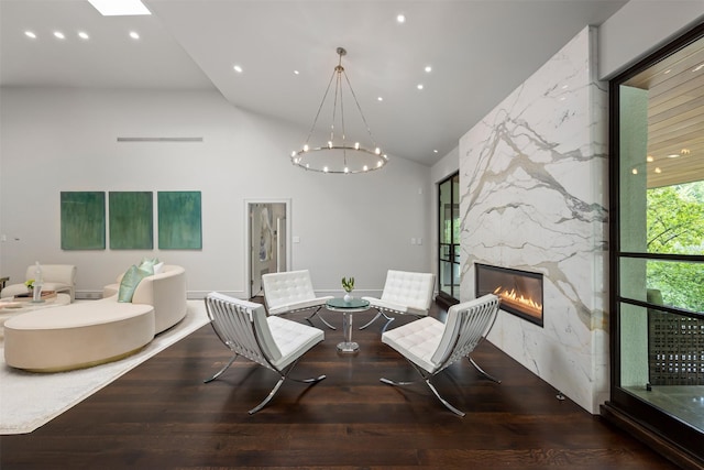 dining area with a high end fireplace, a towering ceiling, hardwood / wood-style flooring, and a notable chandelier