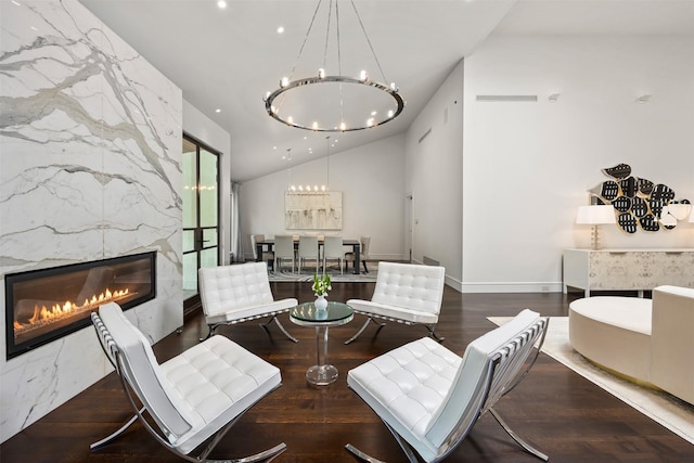 interior space with vaulted ceiling, an inviting chandelier, a fireplace, and dark wood-type flooring