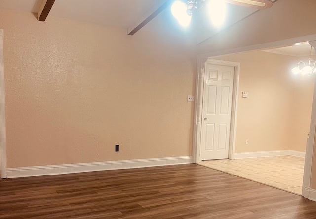 unfurnished room with hardwood / wood-style floors, ceiling fan with notable chandelier, and lofted ceiling with beams