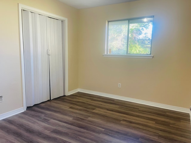 unfurnished bedroom with a closet and dark hardwood / wood-style floors