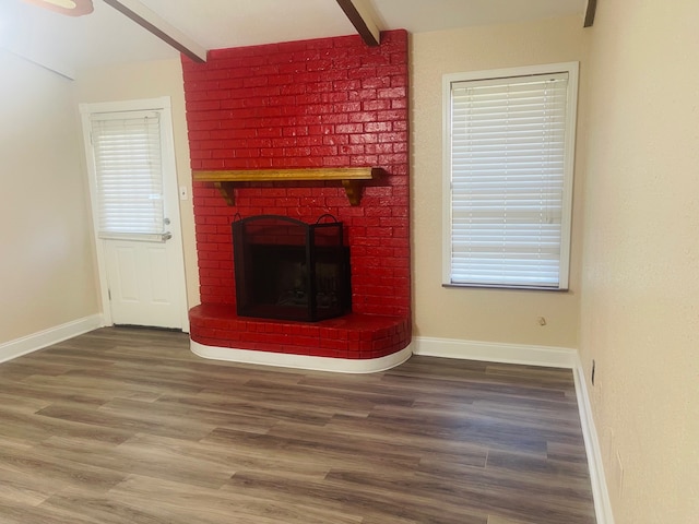 unfurnished living room with a fireplace, a wealth of natural light, beamed ceiling, and wood-type flooring